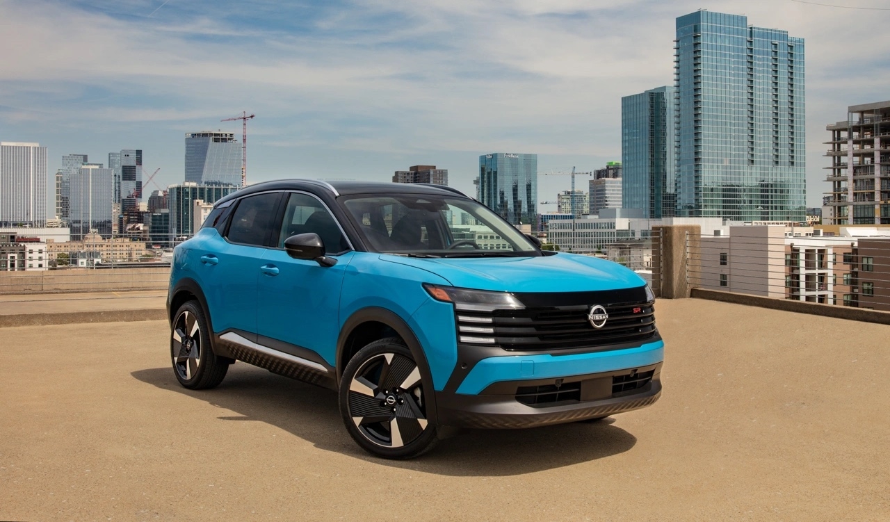 Nissan Kicks 2026 bleu en vue trois quarts avant sur un toit de stationnement urbain avec gratte-ciel en arrière-plan.