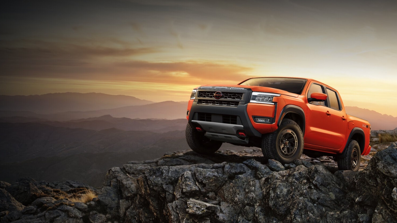 vue latérale avant d'un Nissan Frontier 2025 au sommet d'un rocher au crépuscule