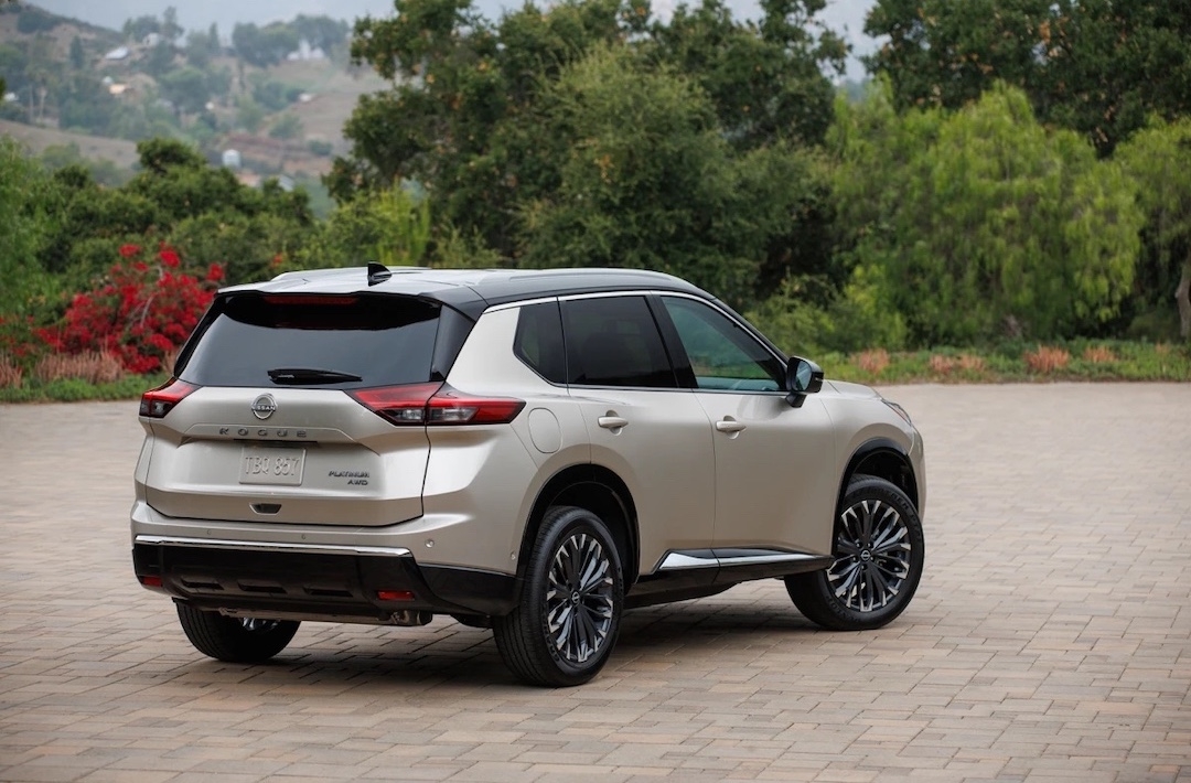 Vue arrière du Nissan Rogue 2025 Platinum beige stationné sur une allée pavée, mettant en valeur son élégance et son design haut de gamme.