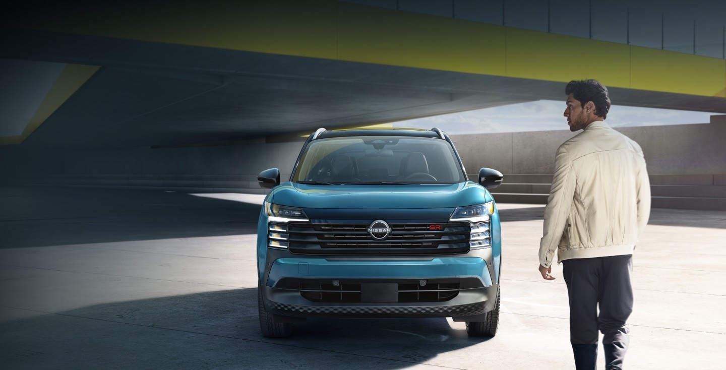 Vue avant du Nissan Kicks 2025 bleu stationné sous un pont urbain, mettant en valeur son design moderne et son format compact idéal pour la conduite en ville.