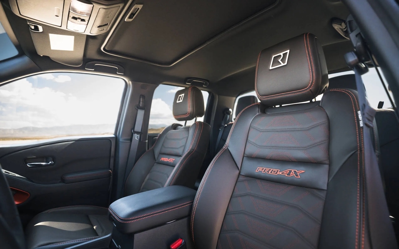 Intérieur du Nissan Frontier 2026 PRO-4X, montrant les sièges en cuir noir avec surpiqûres rouges et appuie-têtes embossés.
